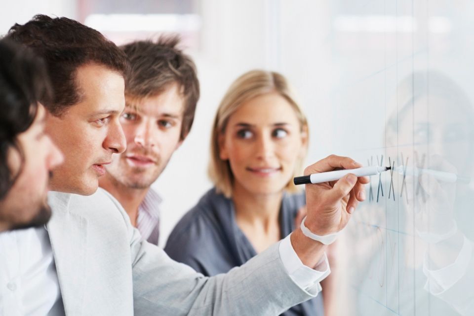 A team discussing a project around an office whiteboard